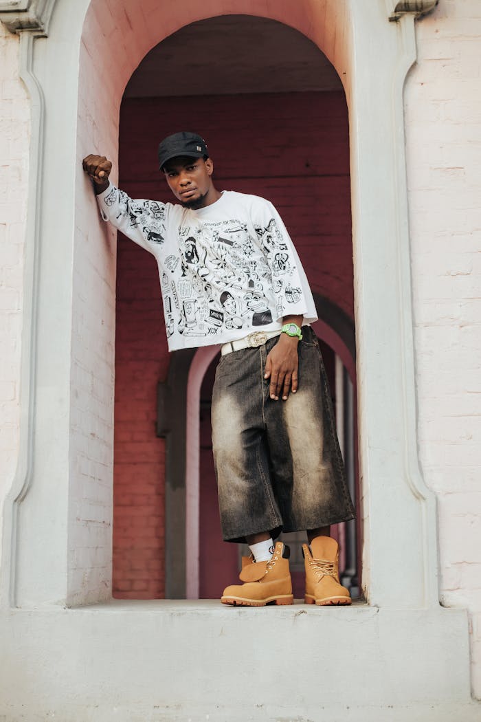 Trendy man in urban outfit posing confidently in ornate archway.